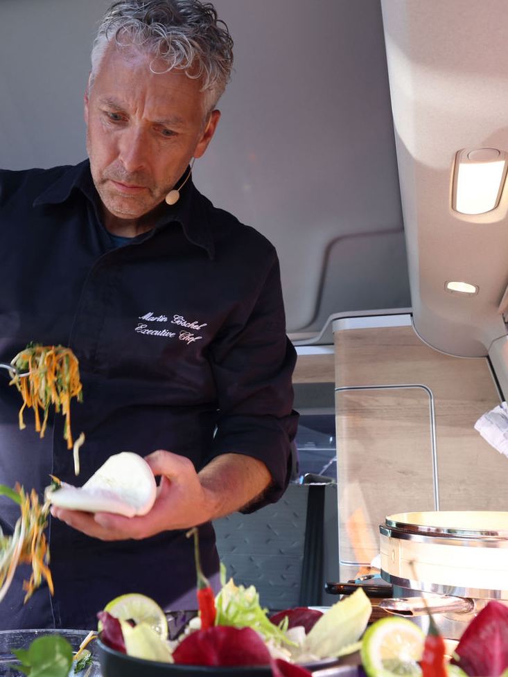 En man lagar mat i en VW husbil på scenen