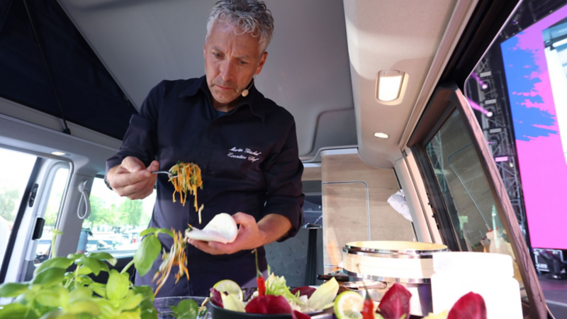 A man from the stage programme prepares food in a VW Camper Van.