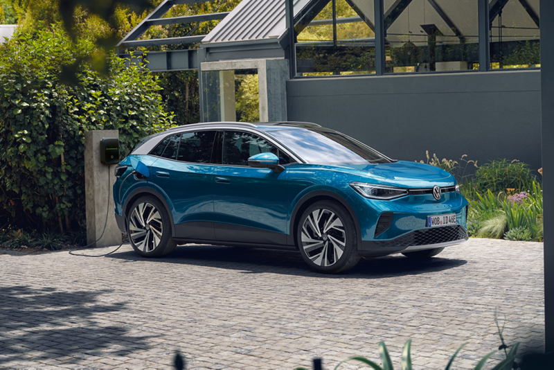 en vw id4 står parkert utenfor et hus og lader