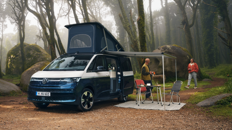 Ein VW California auf einer Lichtung im Wald.