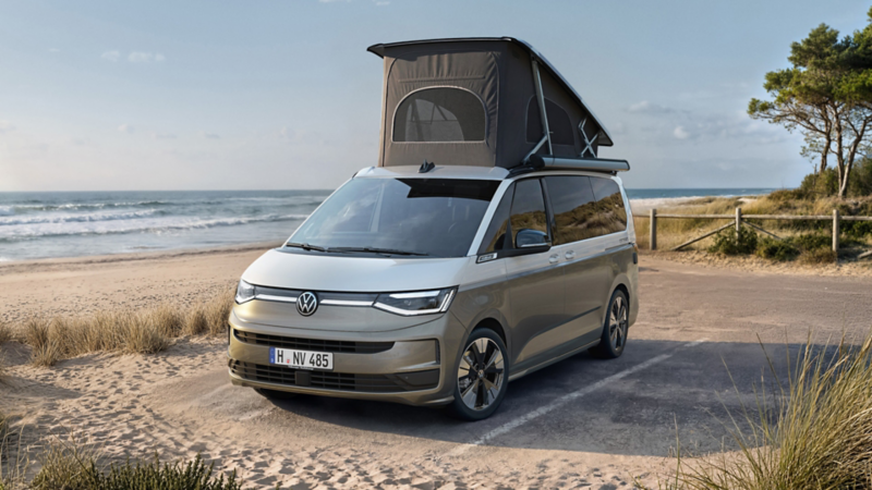 VW California mit aufgeklapptem Dachzelt parkt direkt am Strand mit Blick aufs Meer