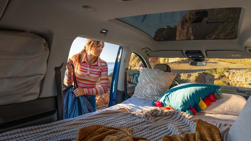 Women laughing in the Volkswagen Caddy California and looking out of the back door. 