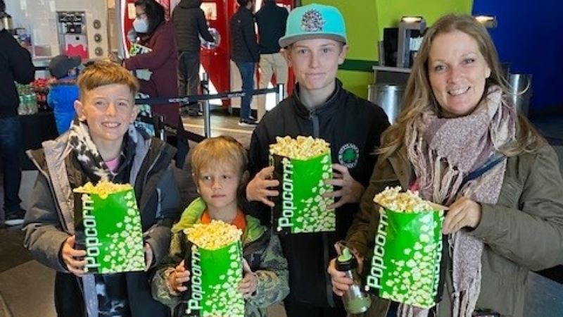 A mother and her sons holding popcorn before the movie.