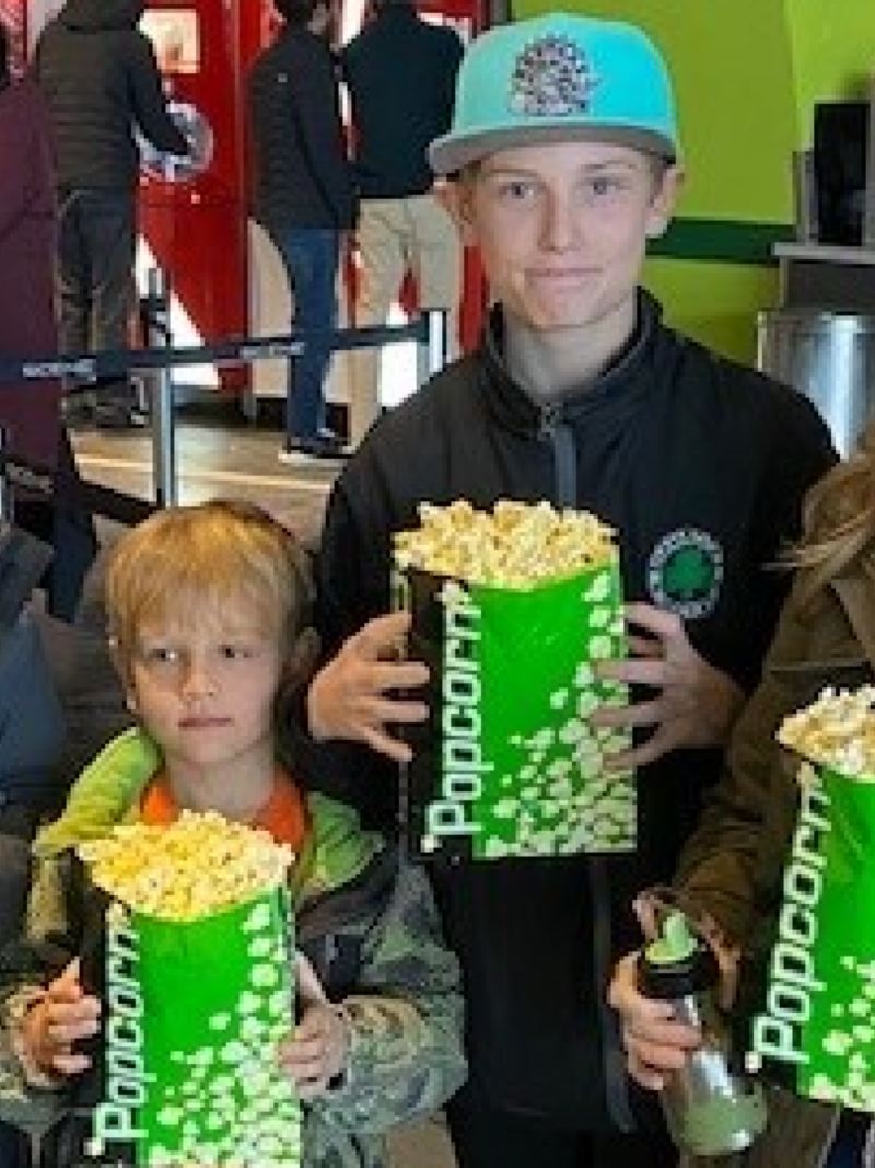 Une mère et ses fils tiennent des sacs de maïs soufflé avant le film.
