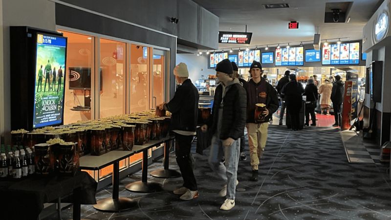 4 friends grabbing free popcorn before going into the theatre.