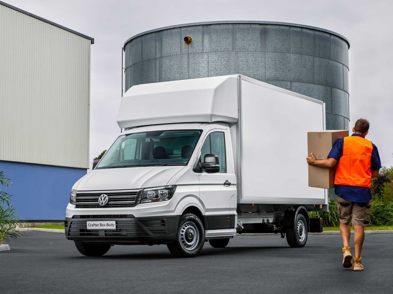Delivery boy with box moving towards Volkswagen Crafter Box Body