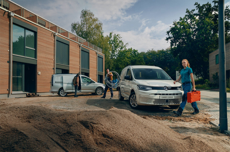 Biały Volkswagen Caddy Furgon dynamicznie przejeżdża przez miasto.