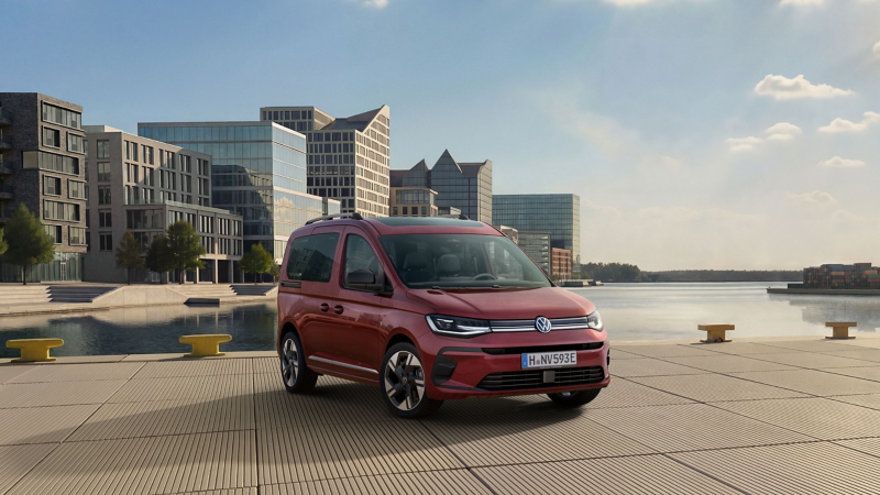 Der VW Caddy eHybrid parkt auf einer Fläche am Wasser, im Hintergrund befindet sich eine Stadt.