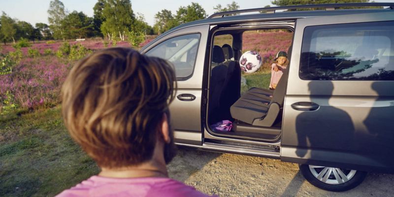 Un bambino lancia una palla attraverso la porta scorrevole aperta di Volkswagen Caddy Kombi.