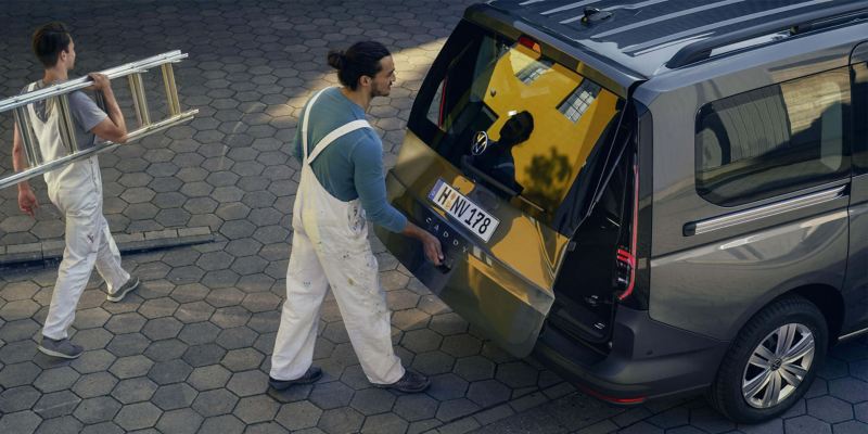Два маляра загружают инструменты в VW Caddy Kombi
