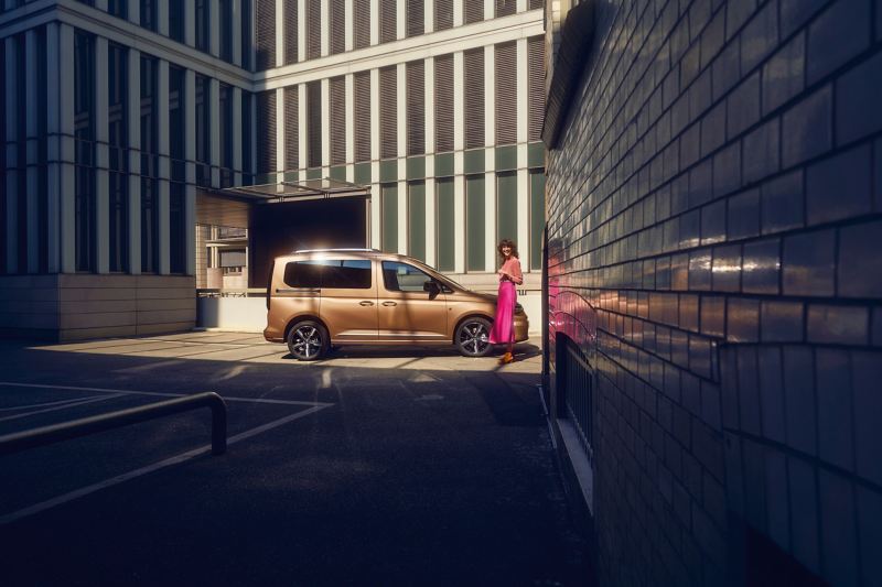Nowy Volkswagen Caddy i rodzina przed nowoczesnym budynkiem.