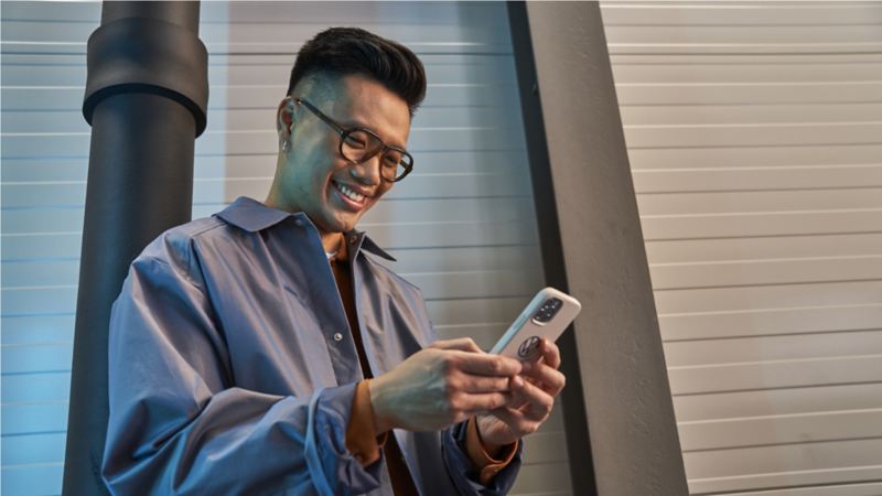 man with glasses and a blue jacket looking down at his phone