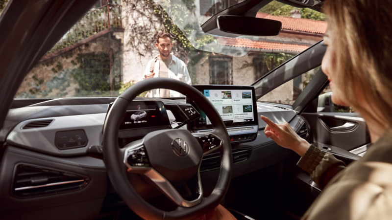 Eine Hand bedient das zentrale Touchdisplay und wählt digitale Fahrzeugfunktionen im Infotainmentsystem aus.