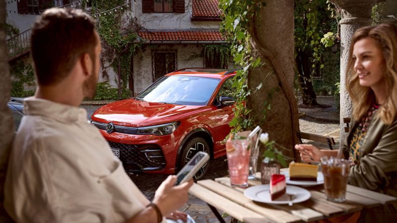 Un couple est assis à une table, en arrière-plan une Volkswagen.