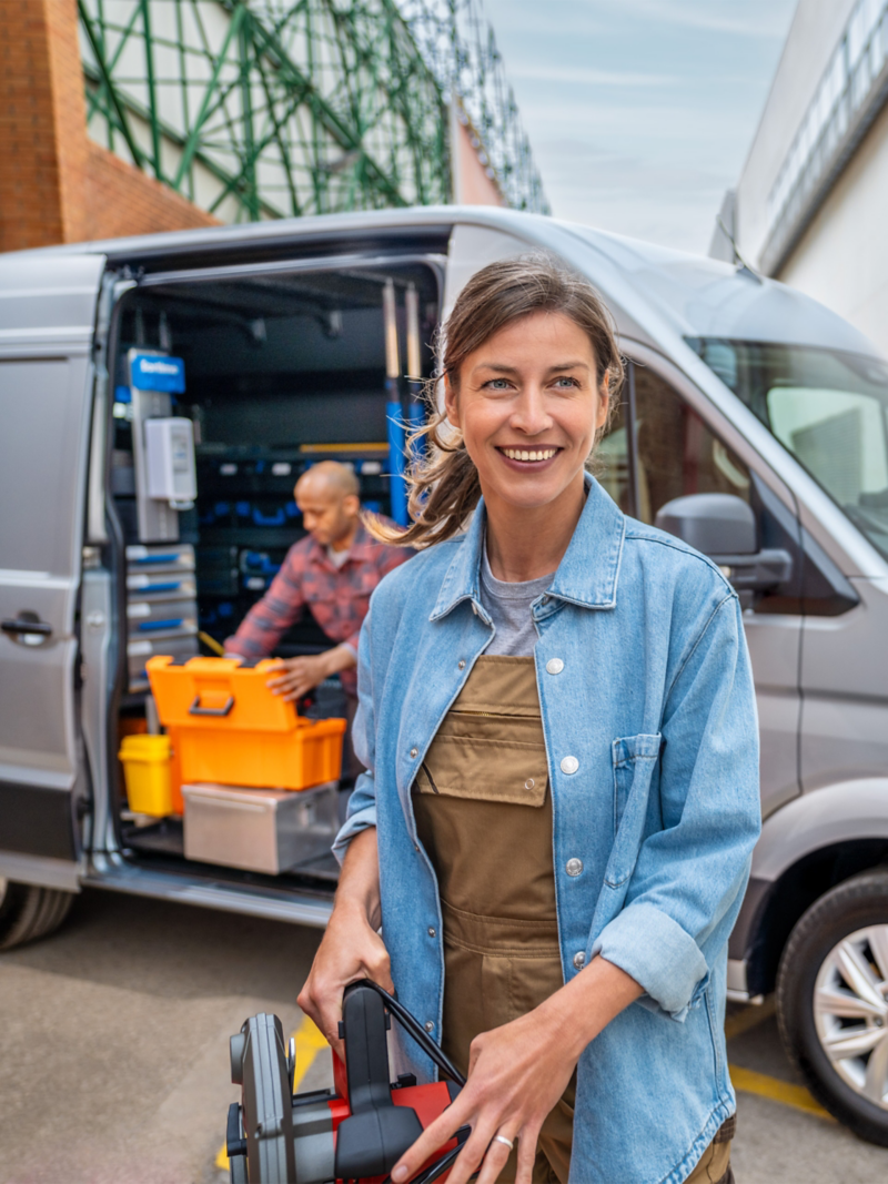 Zwei Handwerker laden ihr Werkzeug aus einem grauen VW Crafter.