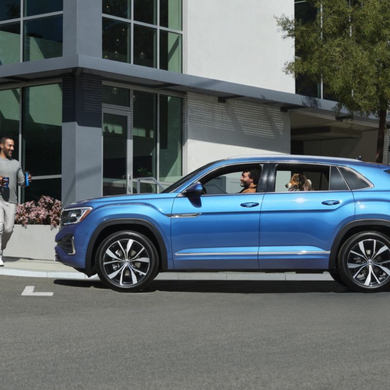 The Kingfisher Blue Metallic 2024 Volkswagen Atlas Cross Sport parked near a house on the street