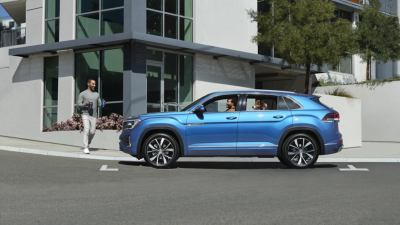 The Kingfisher Blue Metallic 2024 Volkswagen Atlas Cross Sport parked near a house on the street