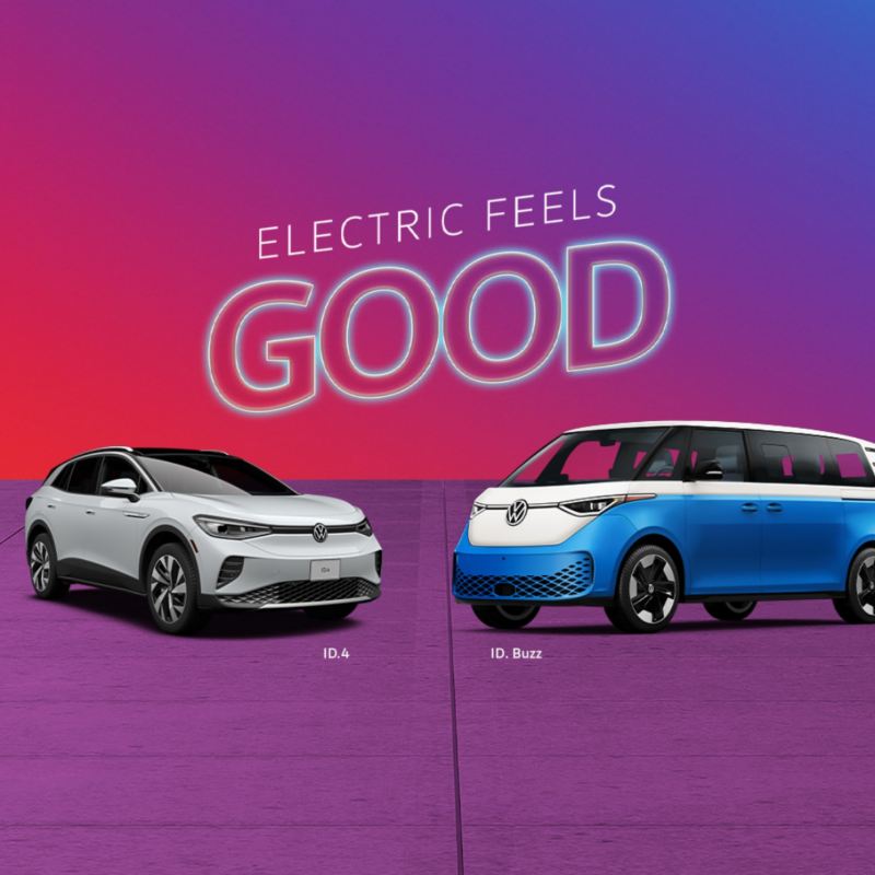 The 2024 grey Volkswagen ID. 4 and white and blue ID. Buzz parked near each other with “Electric Feels Good” sign above.