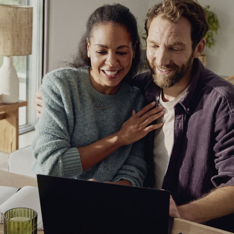 Un homme et une femme regardent un écran d’ordinateur portable à la maison