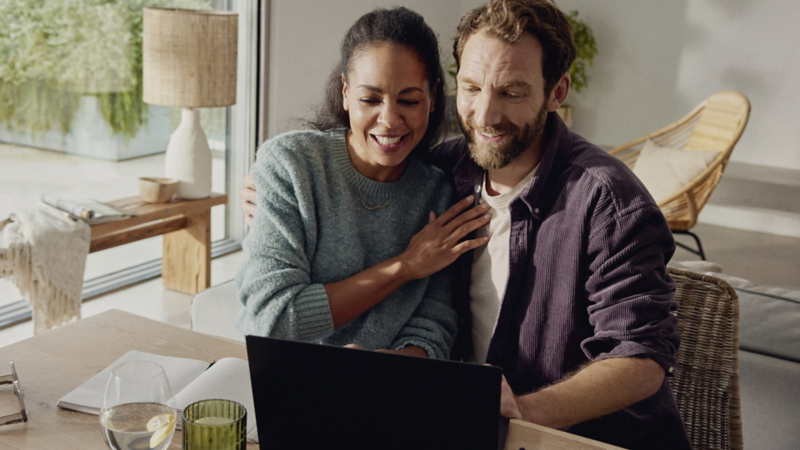 A man and a woman looking at the screen of the laptop at home