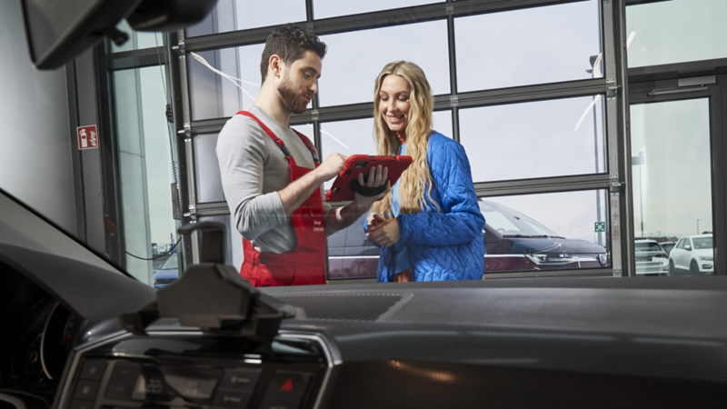 Un technicien automobile montre quelque chose sur son écran à une cliente.