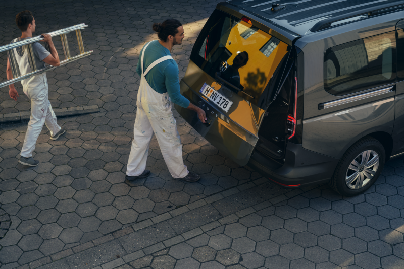 Un hombre abriendo el portón trasero del VW Caddy Cargo.