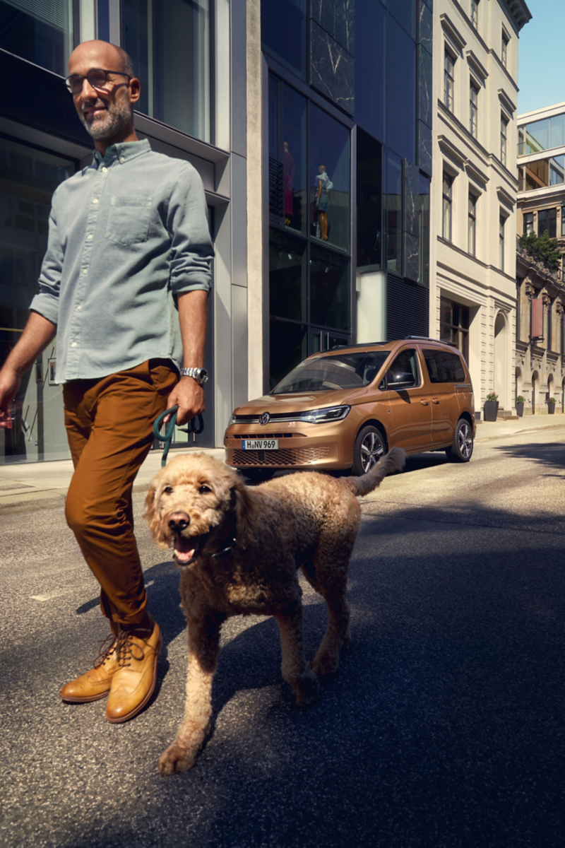 A man walking his dog in front of the caddy