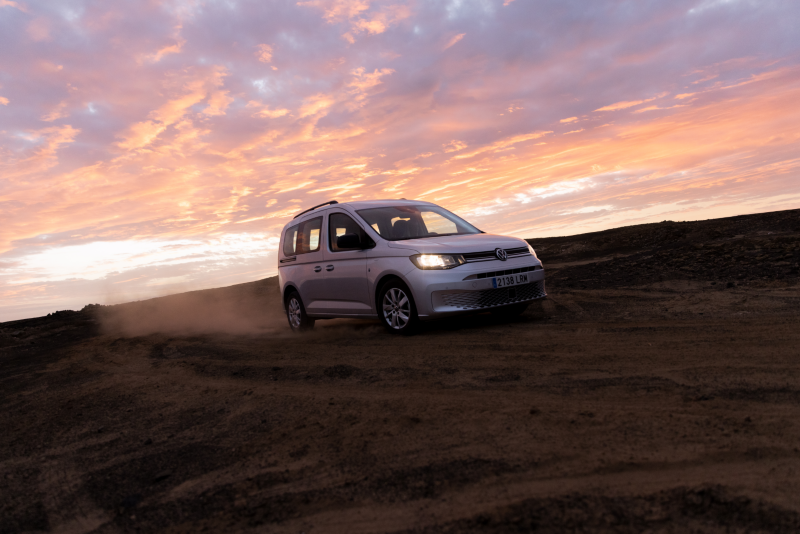 Vista frontal lateral del VW Caddy en una carretera junto a la playa.