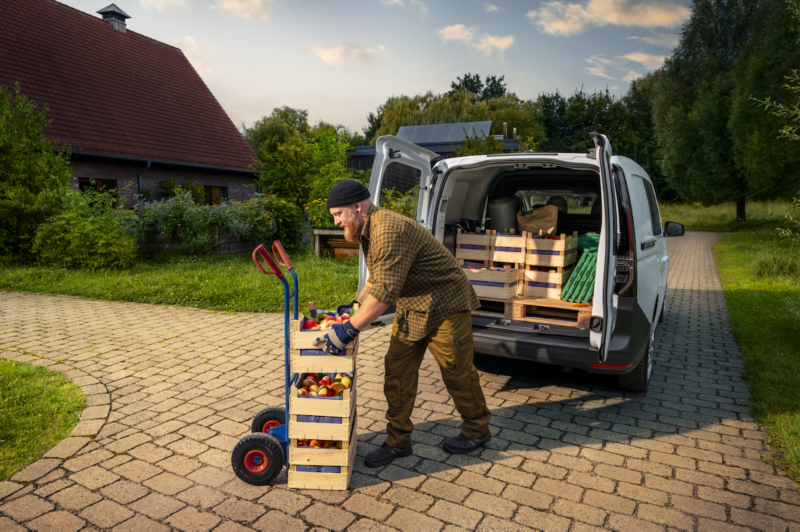 Un hombre descargando cajas del compartimento trasero del VW Caddy Cargo.