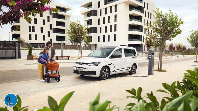 Una familia en la calle cargando el VW Caddy.