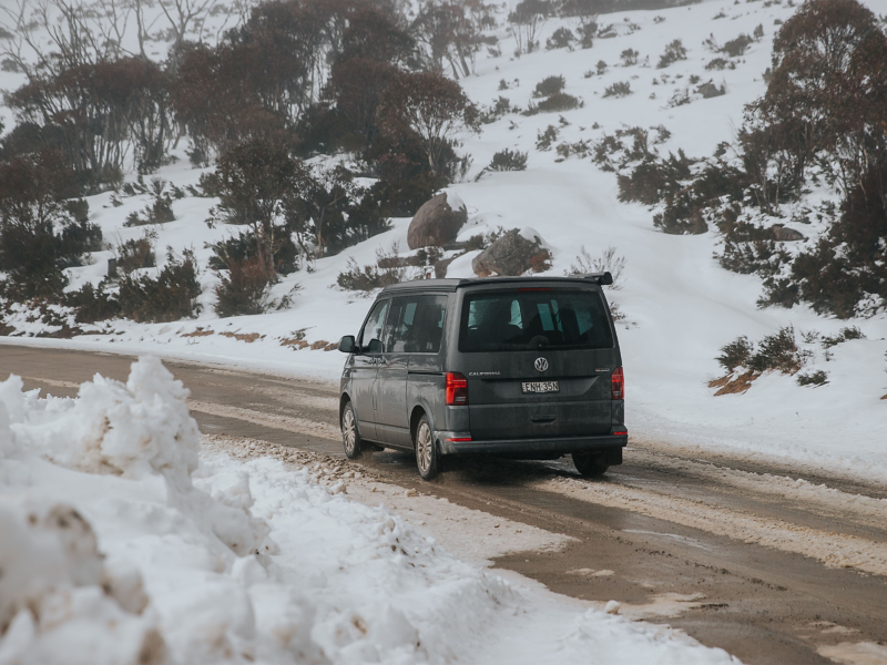 VW van driving through snowy mountain road