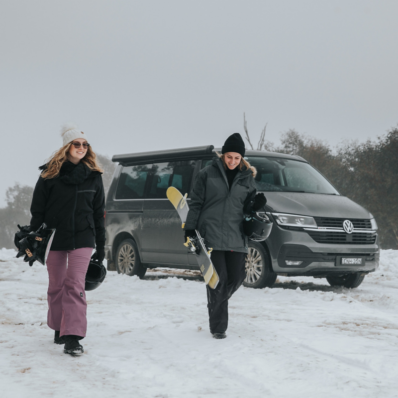 Image of skier & snowboarder with VW California in background