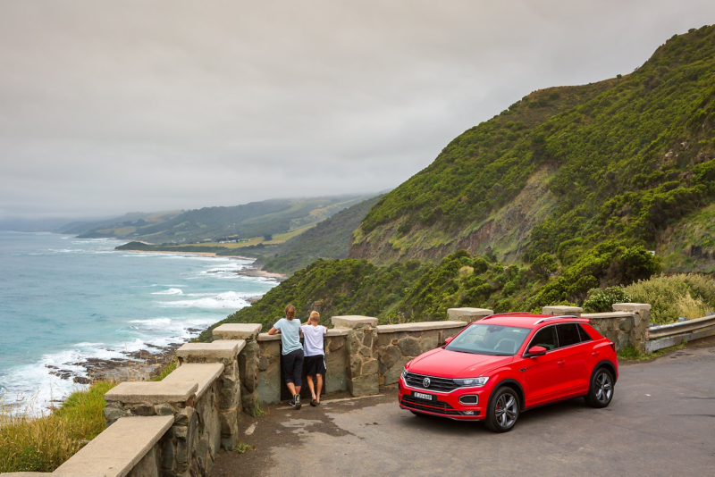 VW car parked up with two people looking out to sea