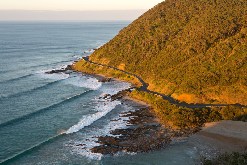 View of ocean and mountain with road winding round mountain