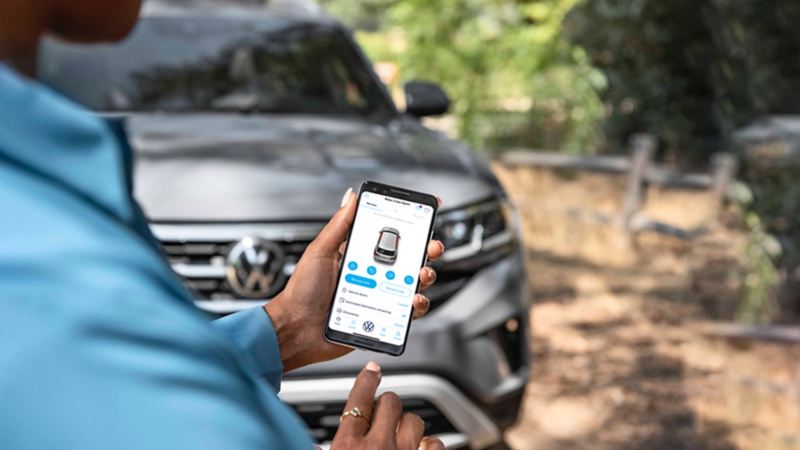 Car-Net® app being used on a phone with a VW car in the background