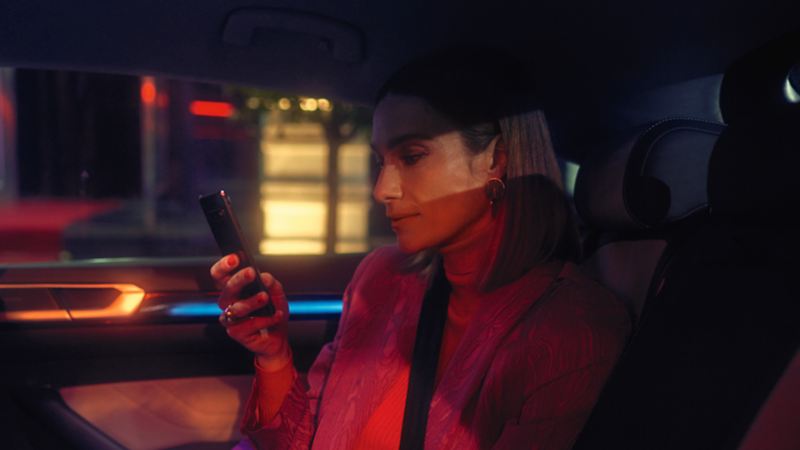 Une femme en voiture regarde son téléphone portable