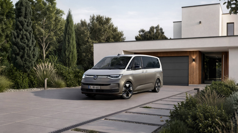 A sleek, modern van is parked in front of a contemporary house with large windows. The setting features lush green trees and a well-maintained garden, conveying a serene and stylish atmosphere.