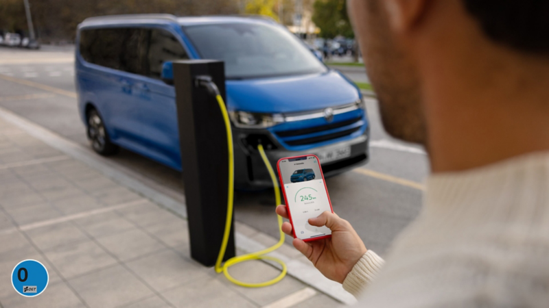 Un hombre revisando con el teléfono móvil la carga del VW Nuevo e-Caravelle.