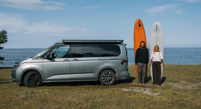 Kreatörerna Caroline och Sebastian med varsin surfingbräda bredvid VW California.