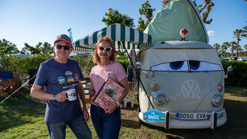 Un hombre y una mujer de pie delante de una VW T1.