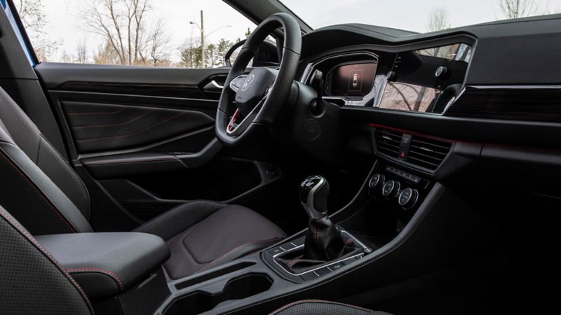 An interior of the 2023 Volkswagen Jetta GLI featuring steering wheel and a gearbox