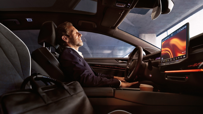 En mand sidder afslappet i en VW ID.7, rat og infotainmentdisplay kan ses.
