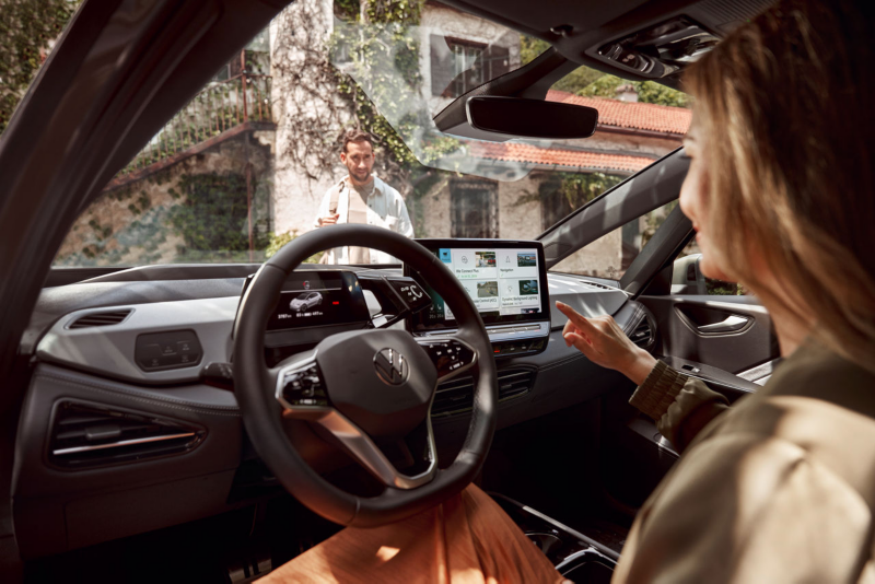 A woman sitting behind the wheel of a VW ID.3 and interacting with the digital display
