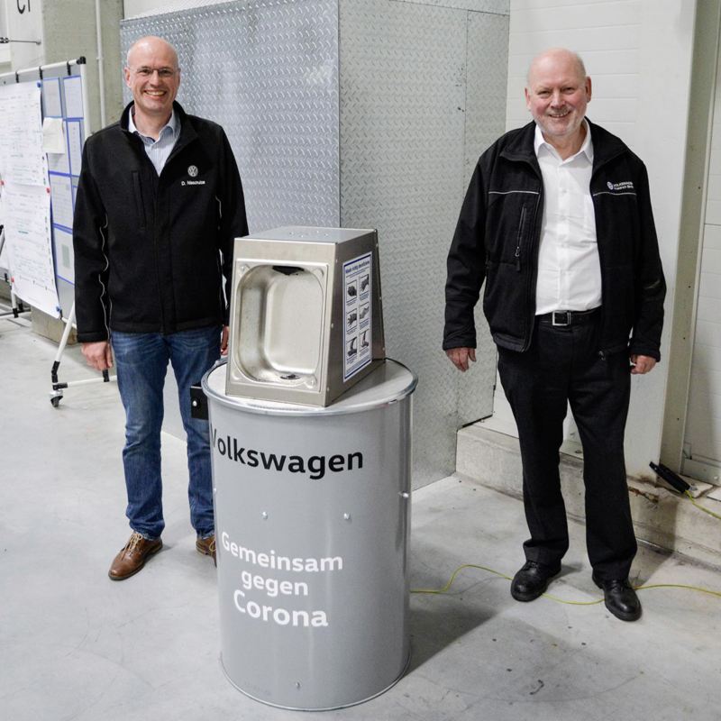 VW Mitarbeiter zeigen Desinfektionsmittelspender gegen Corona im VW Werk Emden