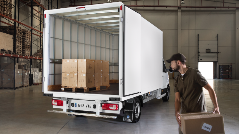 Un trabajador de un almacén cargando cajas de cartón en un VW Crafter Box