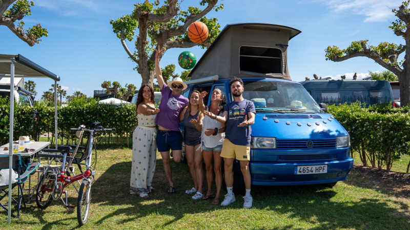 Una familia jugando con balones junto a un VW California.
