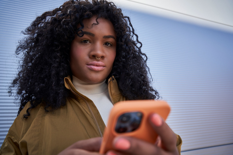 Woman looking at camera holding phone