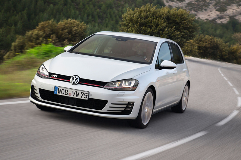 a silver Golf GTI driving along a tree-lined countryside road