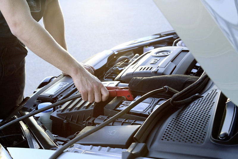 En öppen motorhuv, man ser någon som meckar