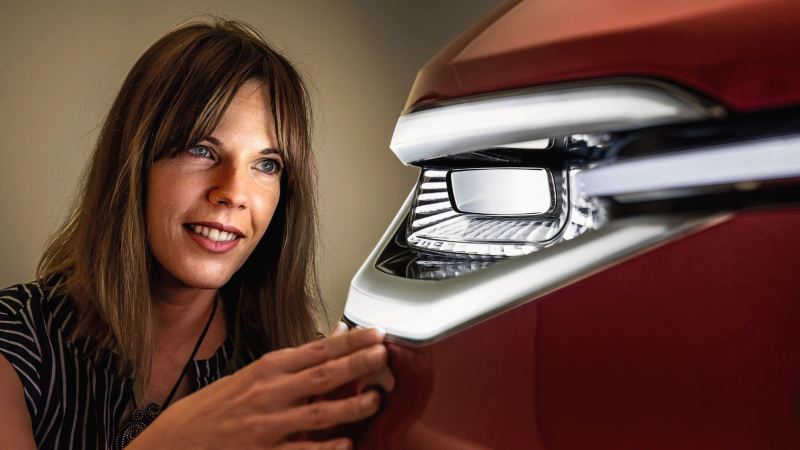 Woman looking at a front light of a car